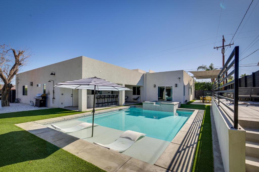 uma casa com piscina e guarda-sol em Modern Palm Springs Home with Pool and Gas Fire Pit! em Palm Springs