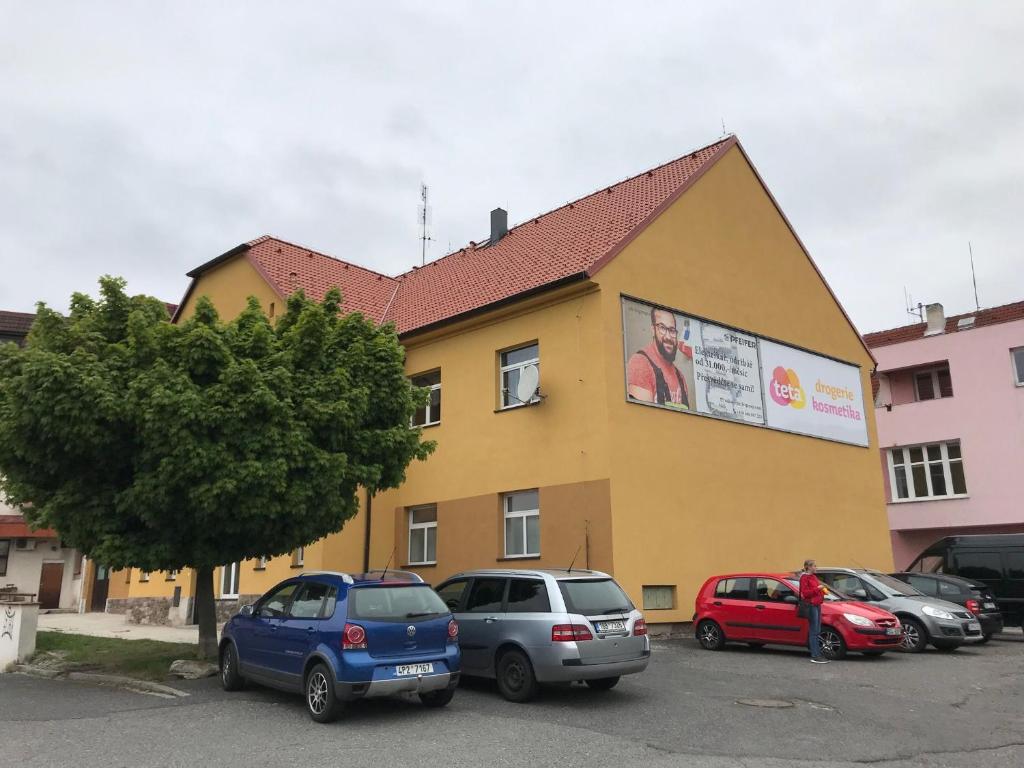 een geel gebouw met auto's geparkeerd op een parkeerplaats bij Hostel RK in Horažďovice