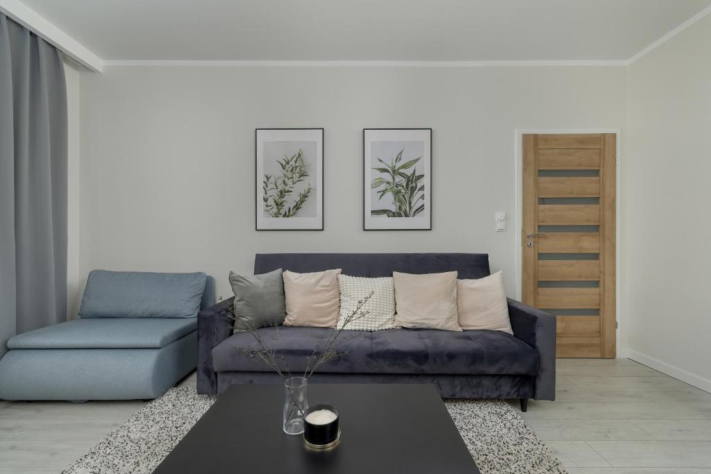 ein Wohnzimmer mit einem blauen Sofa und einem Tisch in der Unterkunft Modern 2-Bedroom Apartment in Krakow by Renters in Krakau