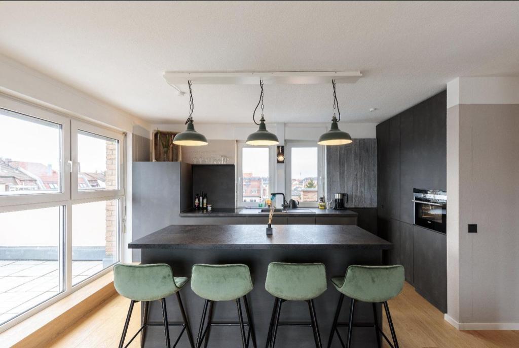 una cucina con isola nera e sgabelli verdi di Designer Penthouse in St Johannes, toller Ausblick über den Dächern Nürnbergs a Norimberga