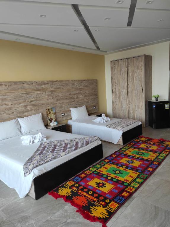 two beds in a room with a rug at pyramids view suite/vista piramidi in Cairo