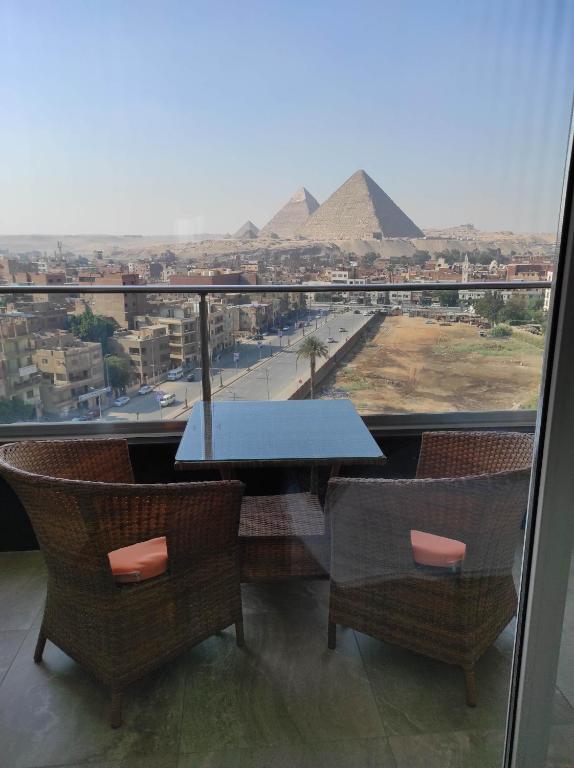 a table and chairs with a view of the pyramids at pyramids view suite/vista piramidi in Cairo