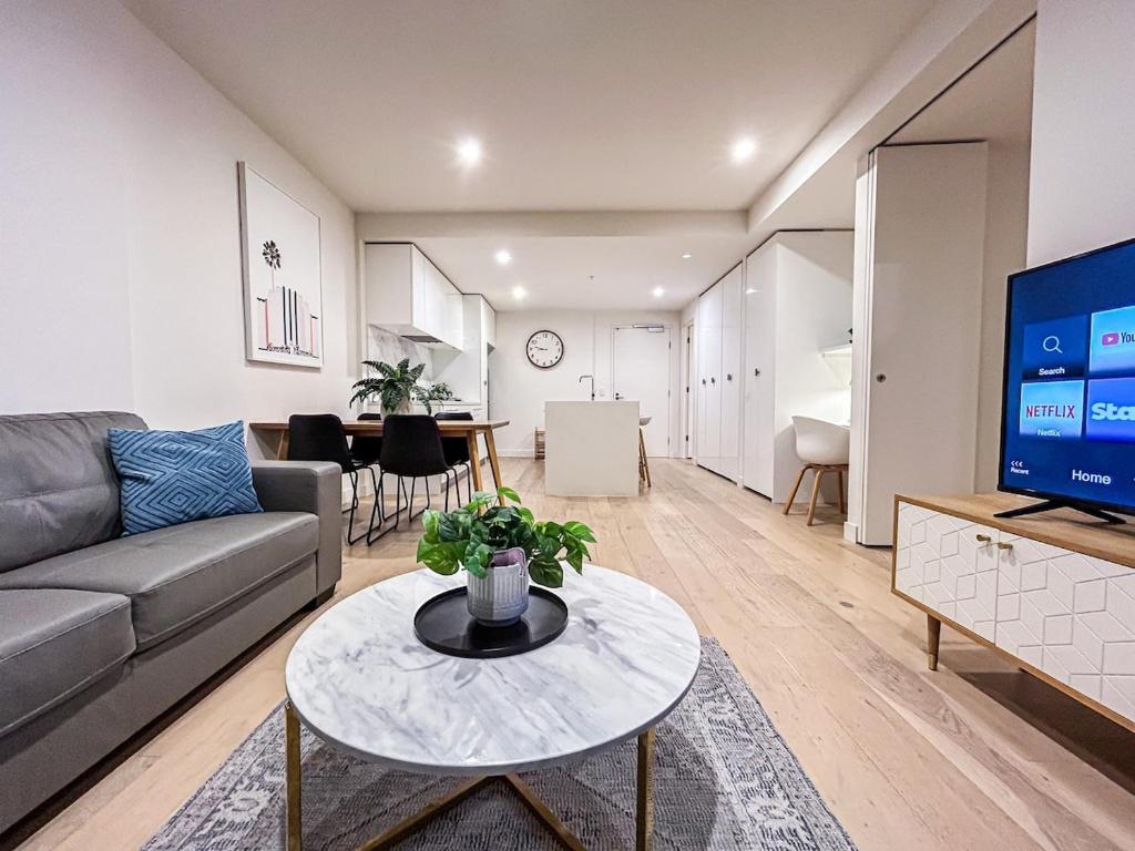 uma sala de estar com um sofá e uma mesa em Close To Mel Uni 2br 2ba Parking Balconywifigy em Melbourne
