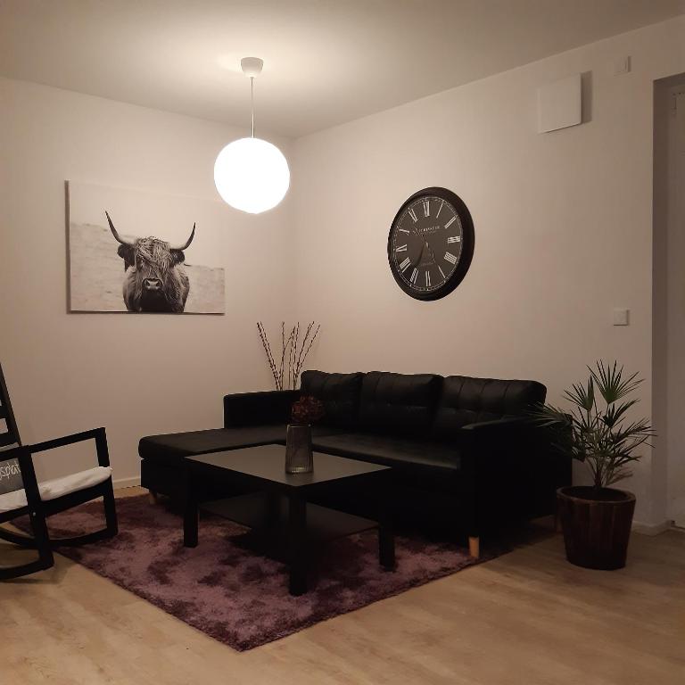 sala de estar con sofá negro y reloj en Ferienwohnung in Hohen Neuendorf bei Berlin, Zentral gelegen, en Hohen Neuendorf