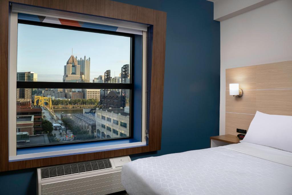 a bedroom with a window with a view of a city at Holiday Inn Express & Suites Pittsburgh North Shore by IHG in Pittsburgh