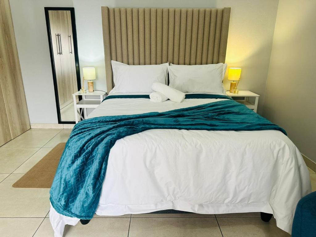 a bedroom with a large bed with a blue blanket at Royal Mansion Lodge in Johannesburg