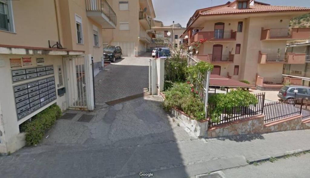 una calle con una valla y algunos edificios en Grazioso appartamento vicino al mare en Giardini Naxos