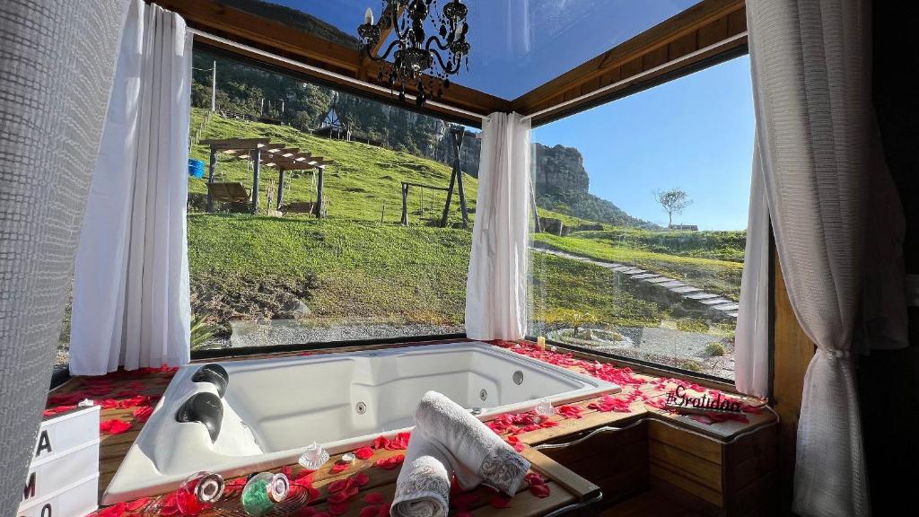 a bath tub in a room with a large window at Refúgio Serra da Tartaruga - Alfredo Wagner in Alfredo Wagner