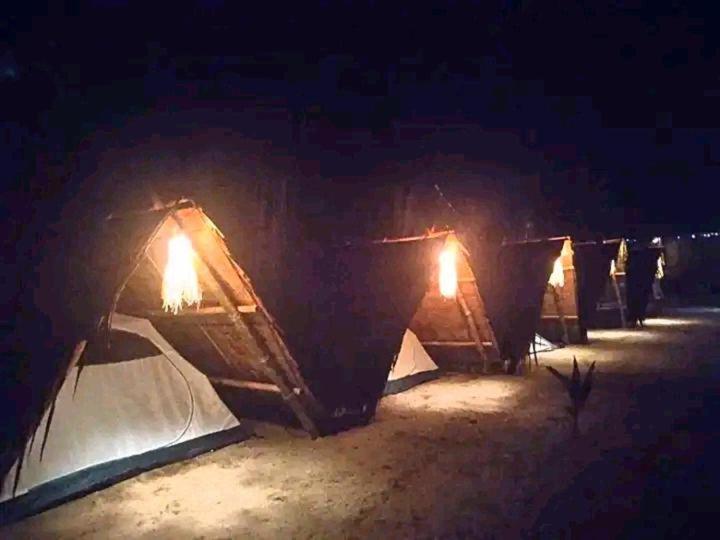 a row of tents in the sand at night at Bucana Kamp Payapa Beachfront in El Nido