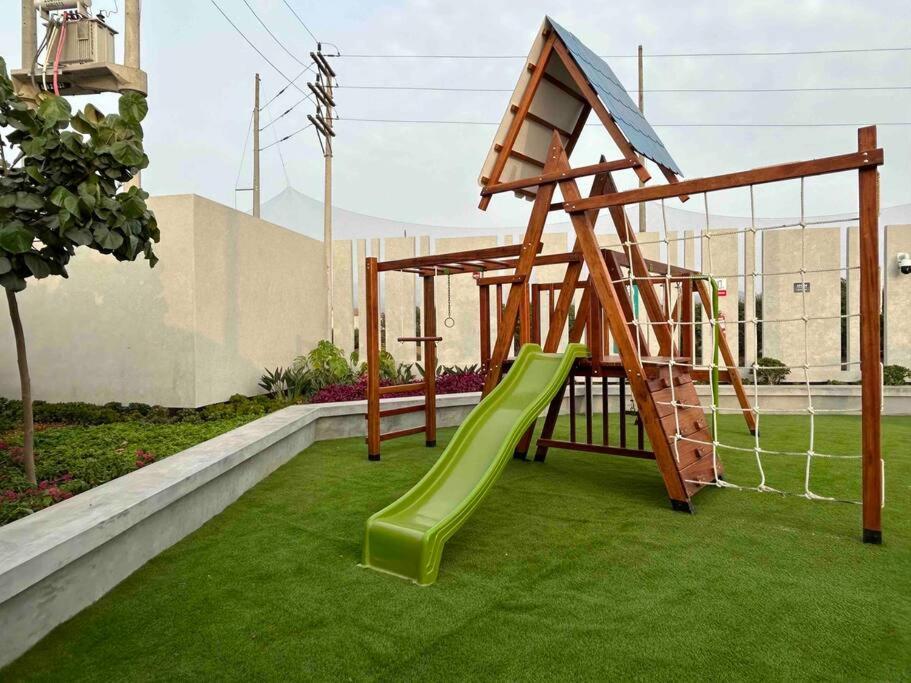 un parque infantil con un tobogán en el césped en Departamento de playa con piscina, en San Bartolo
