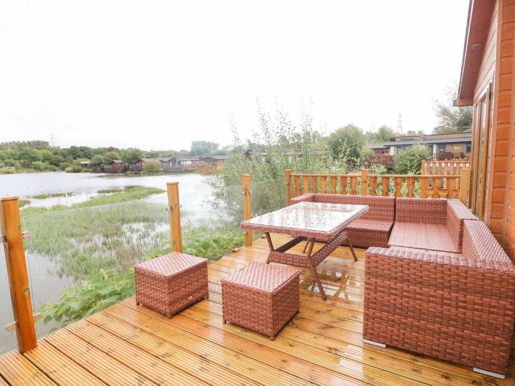 a patio with a table and chairs on a wooden deck at Lakeside 12 in Carnforth