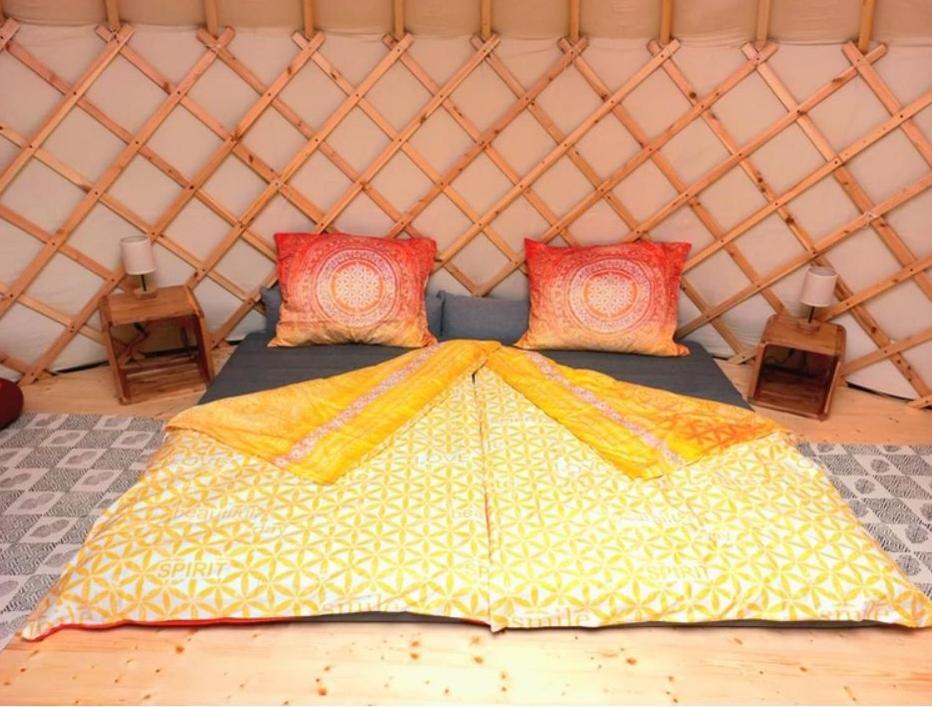 a large bed in a yurt with two tables at Jurte 