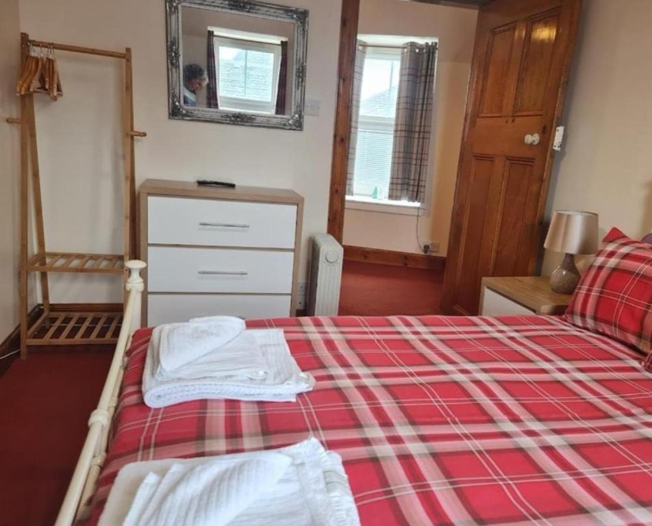 a bedroom with a bed with a red and white blanket at Ness City Apartment in South Kessock