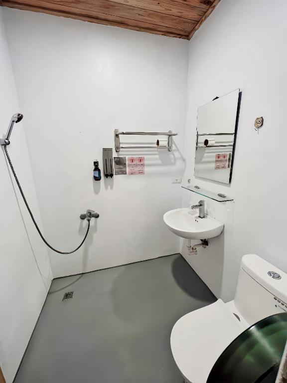 a white bathroom with a toilet and a sink at Kenting Original Hostel in Kenting