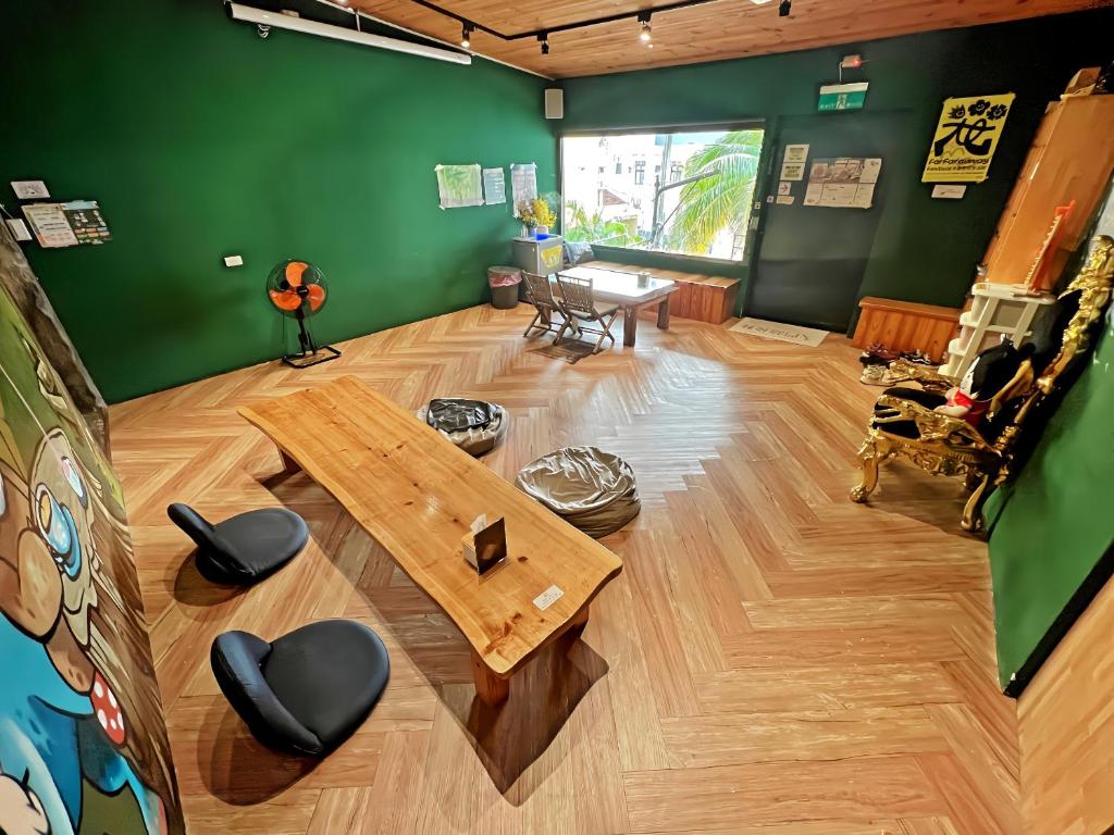 a living room with a wooden table and green walls at Kenting Original Hostel in Kenting