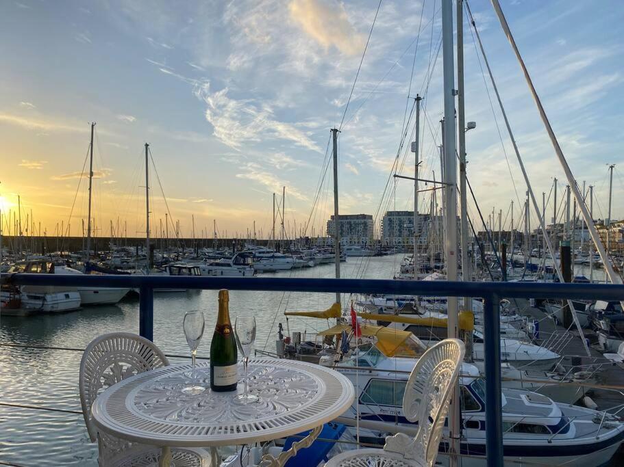 a table with a bottle of wine and chairs on a marina at Seascape - Floating Home at Brighton Marina with free Parking in Brighton & Hove