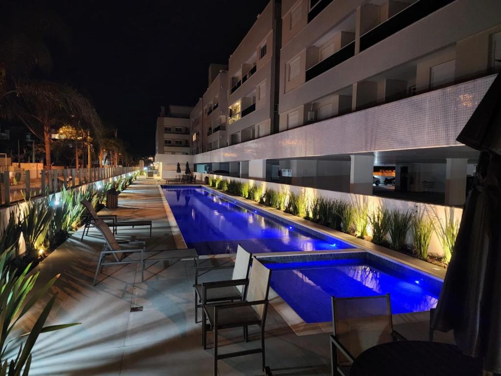 una piscina por la noche con sillas y un edificio en Apto Espetacular 180 m do mar, en Florianópolis