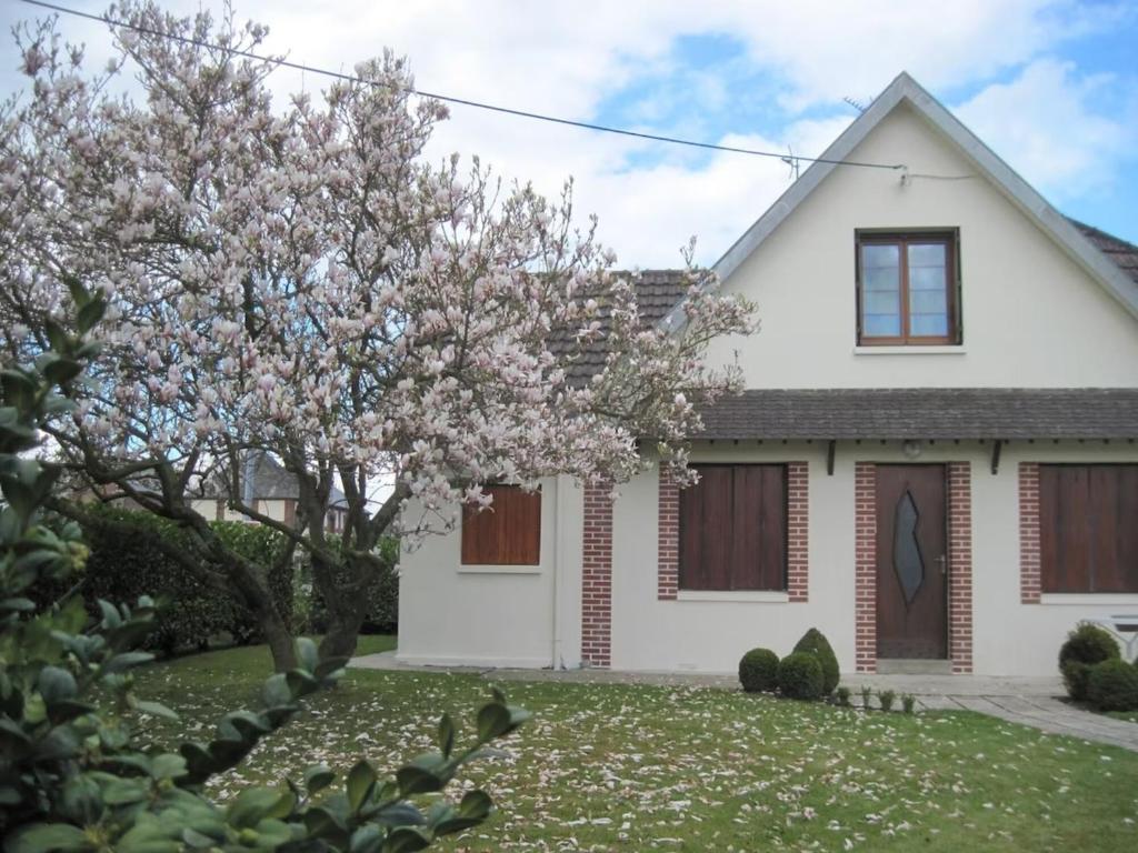 ein weißes Haus mit einem blühenden Baum im Hof in der Unterkunft Le Clos D'aval Le Paulownia in Saint-Nicolas-dʼAliermont