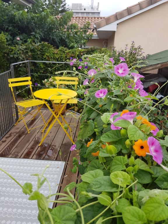 two yellow chairs and a table and flowers on a deck at Chez Hélène in Bordeaux