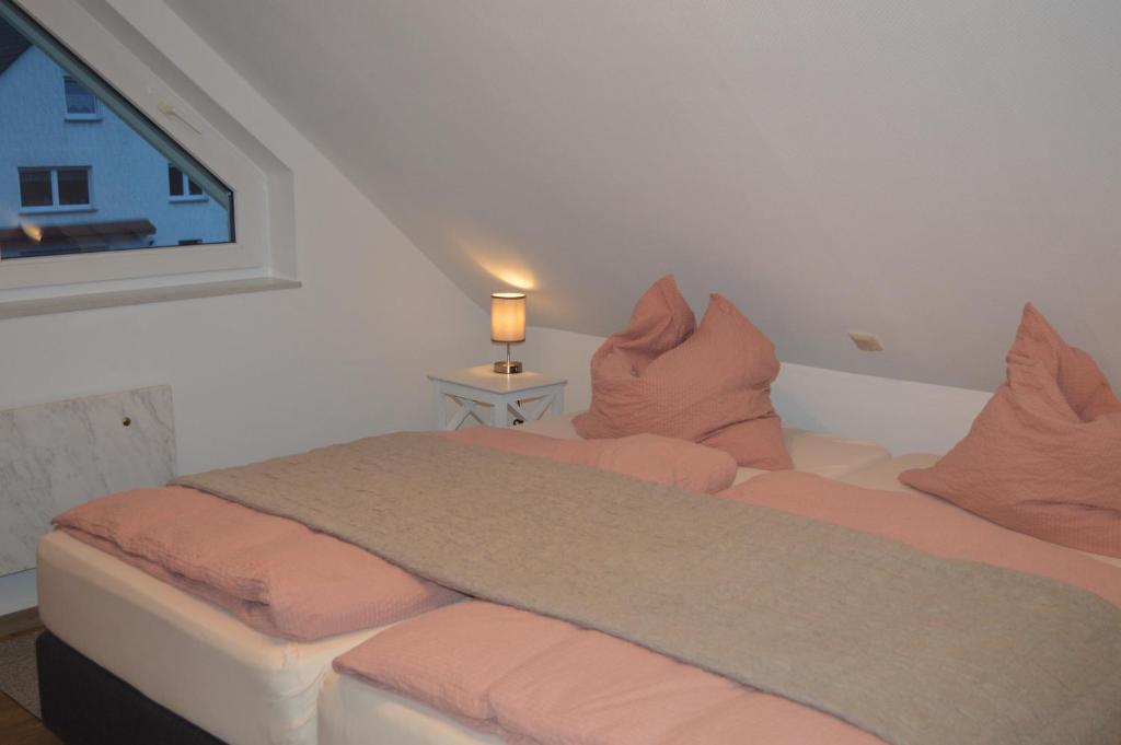 1 Schlafzimmer mit 2 Betten mit rosa Kissen und einem Fenster in der Unterkunft Ferienwohnung Jäger in Hofgeismar in Hofgeismar