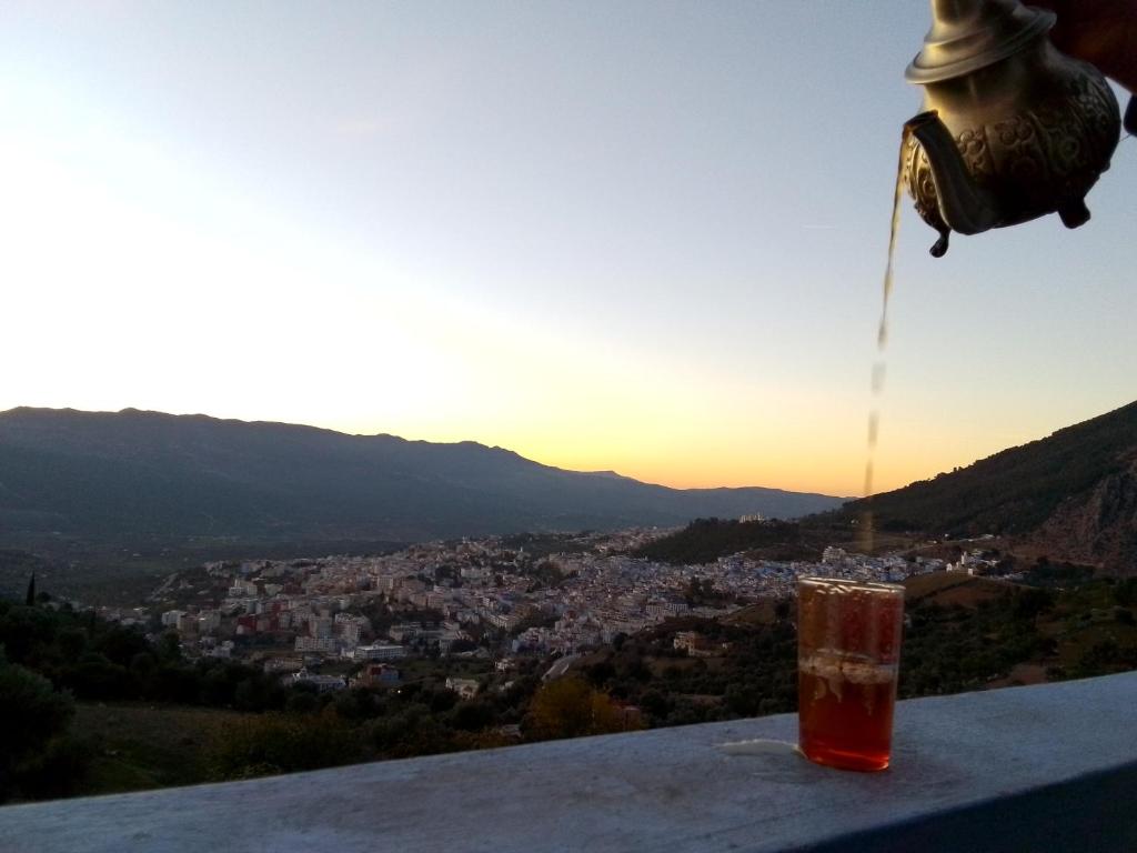 een drankje zittend op een richel met uitzicht op een stad bij Blue House Town in Chefchaouene