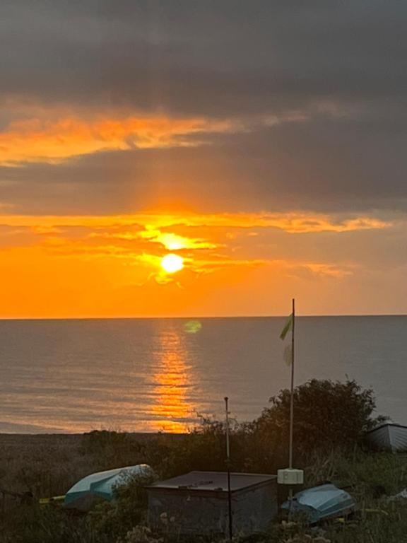 un coucher de soleil sur l'océan avec une voiture et un drapeau dans l'établissement Beautiful 2 bedroom beach getaway, à Pevensey