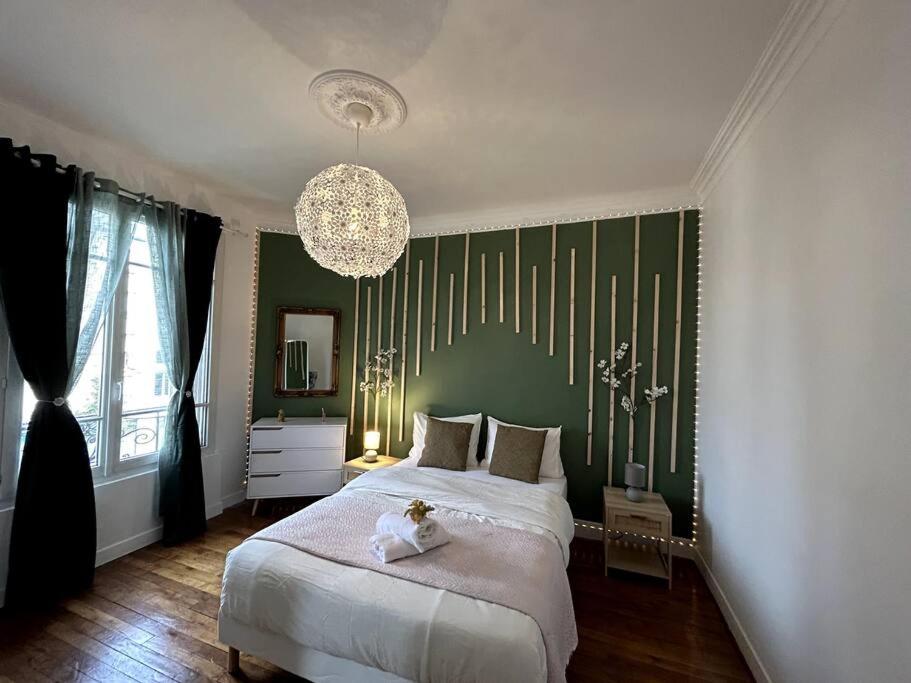una camera da letto con un grande letto con una parete verde di Appartement proche de PARIS au centre ville tout confort a Livry-Gargan