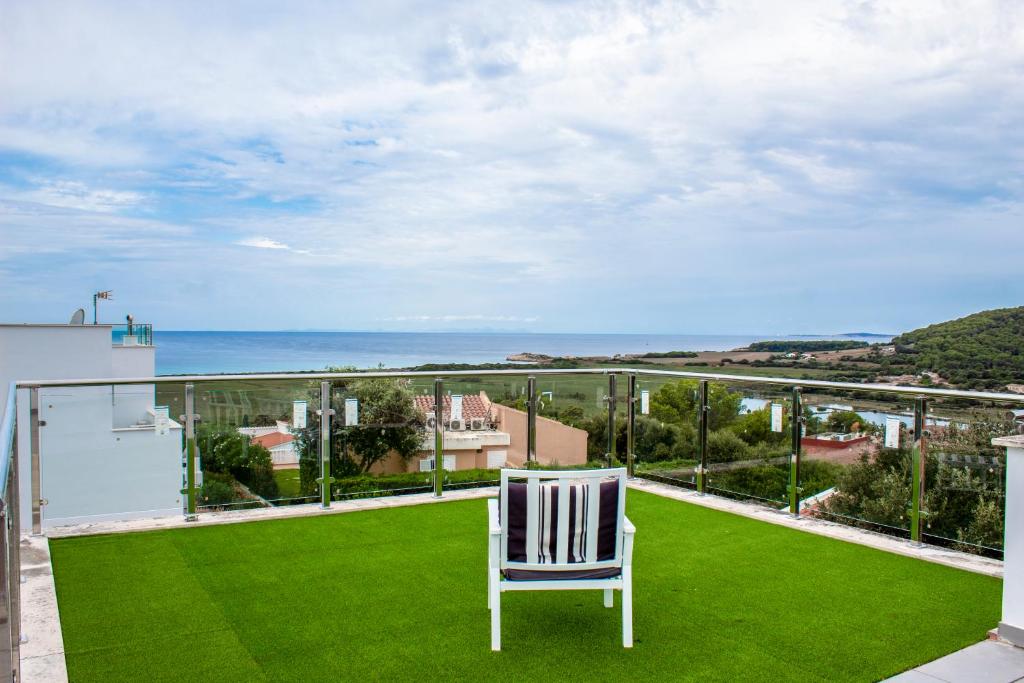 una silla blanca sentada en un balcón con césped verde en Luxury Villa - Amazing Sea Views en Son Bou