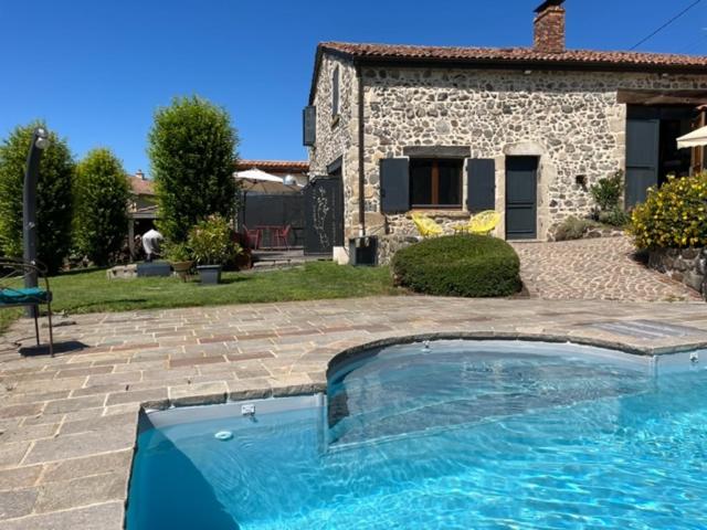 a swimming pool in front of a stone house at Domaine des Pierres D Auvergne in Flat