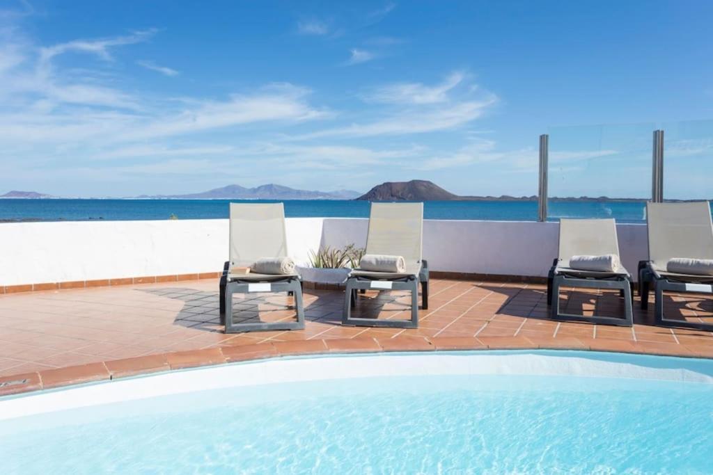 un gruppo di sedie a sdraio accanto alla piscina di Corralejo Beachfront Villa Remos with Lobos Island View, Private Pool, Wifi & BBQ by Amazzzing Travel a Corralejo