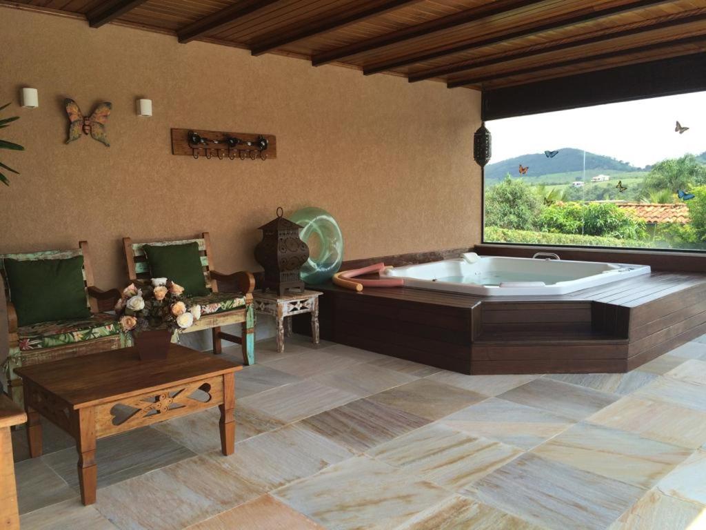 een grote woonkamer met een bad en een tafel bij Suites Casa Maia in Capitólio
