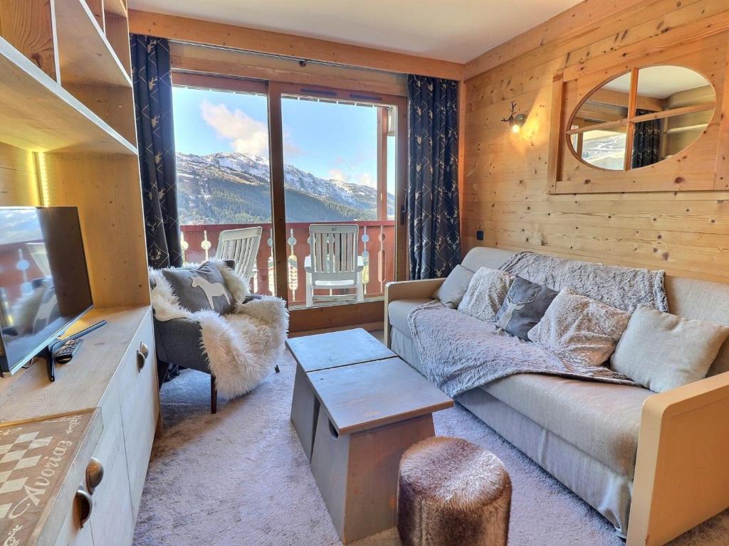 a living room with a couch and a large window at Charmant 2 pièces cabine skis aux pieds, parking inclus - FR-1-182-245 in Les Allues