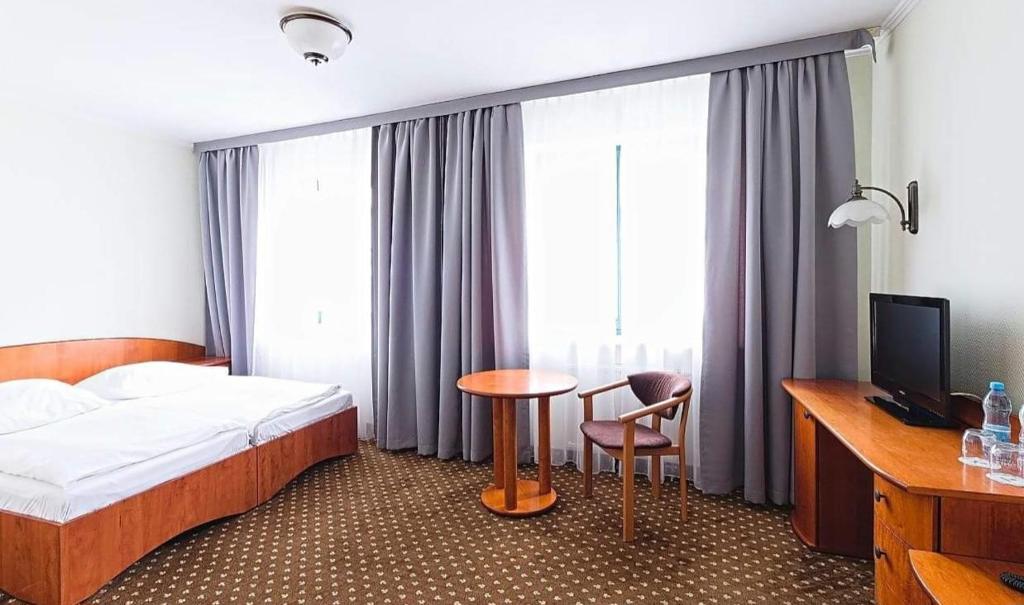 um quarto de hotel com uma cama, uma mesa e cadeiras em Amore Mio Stare Miasto Apartamenty em Elblag