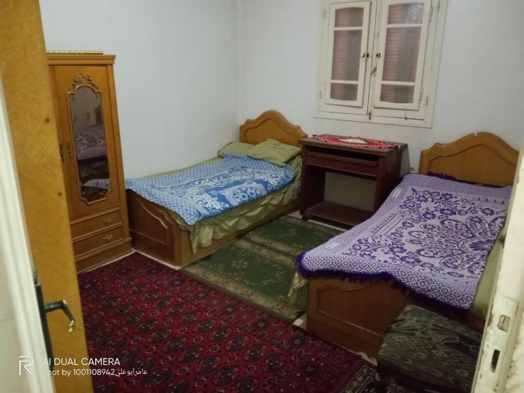 Shaṭṭ `Ezbet el-Laḥm的住宿－شقة مفروشة للايجار ٩٠ م，小房间设有两张床和镜子