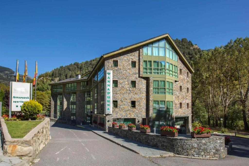 un grande edificio in pietra con piante di fronte di Annapurna M&P a Ordino