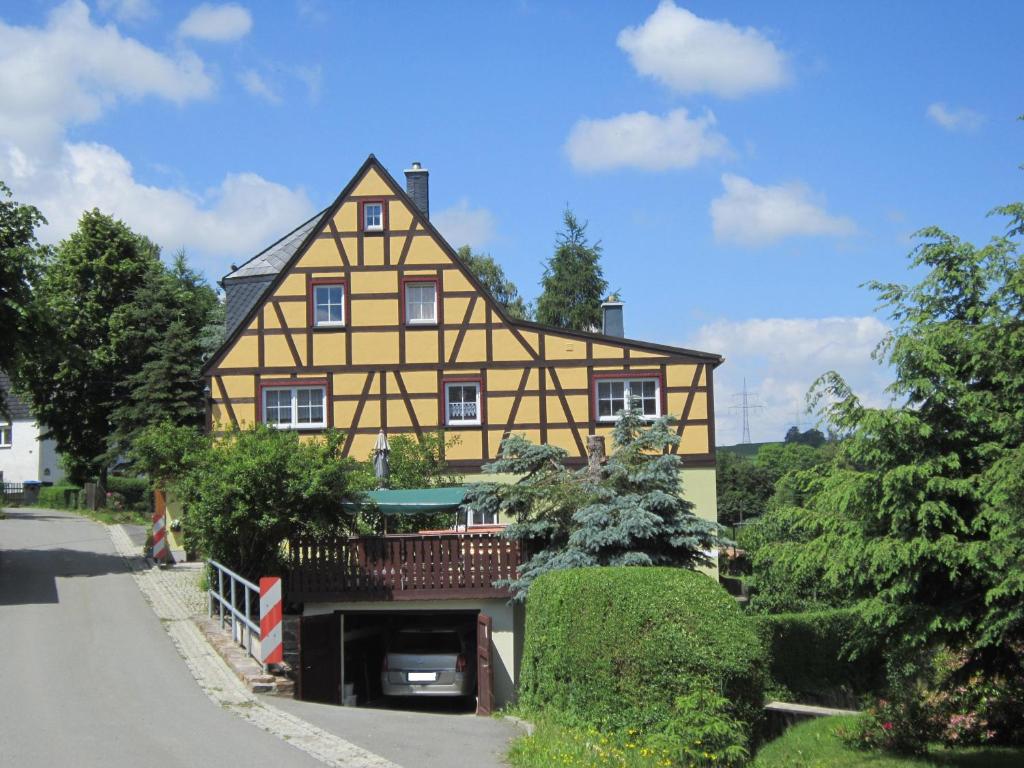 a large yellow and black house with a porch at Haus am Bach Arnsfeld in Arnsfeld