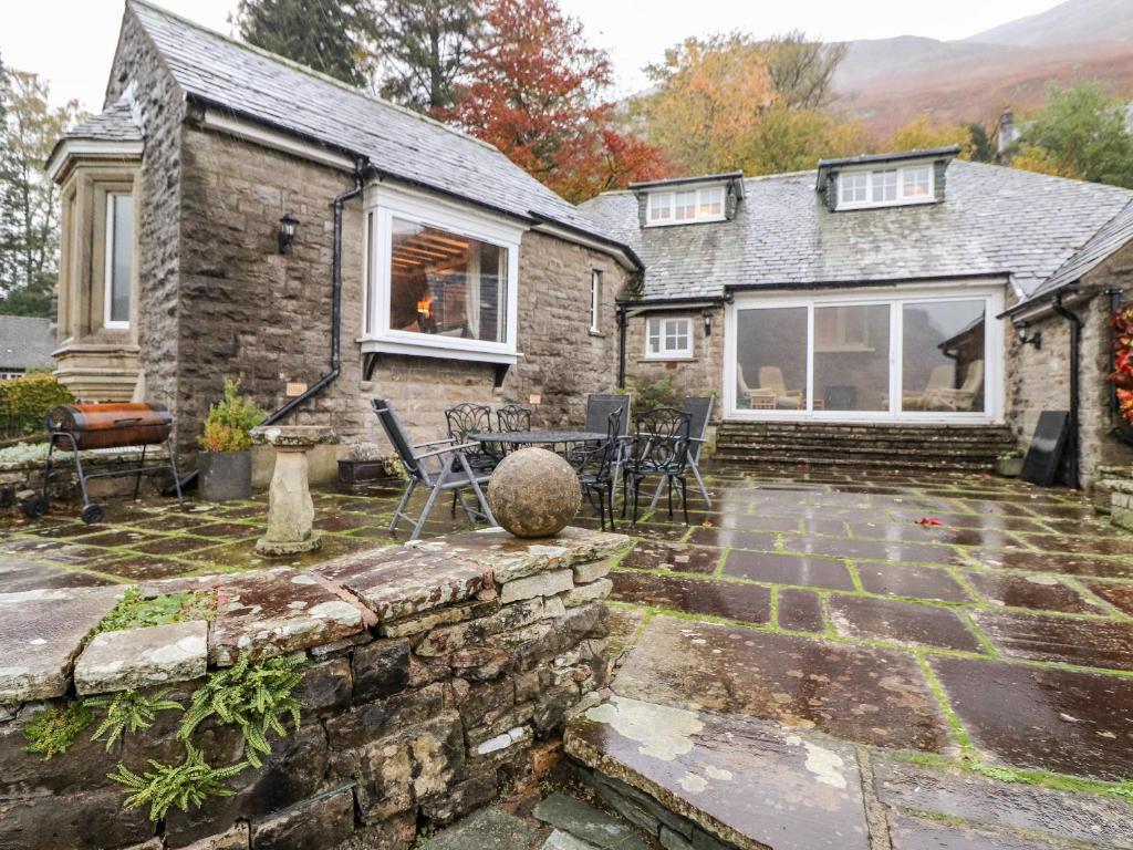 a stone house with a patio with a table and chairs at Grey Walls in Penrith
