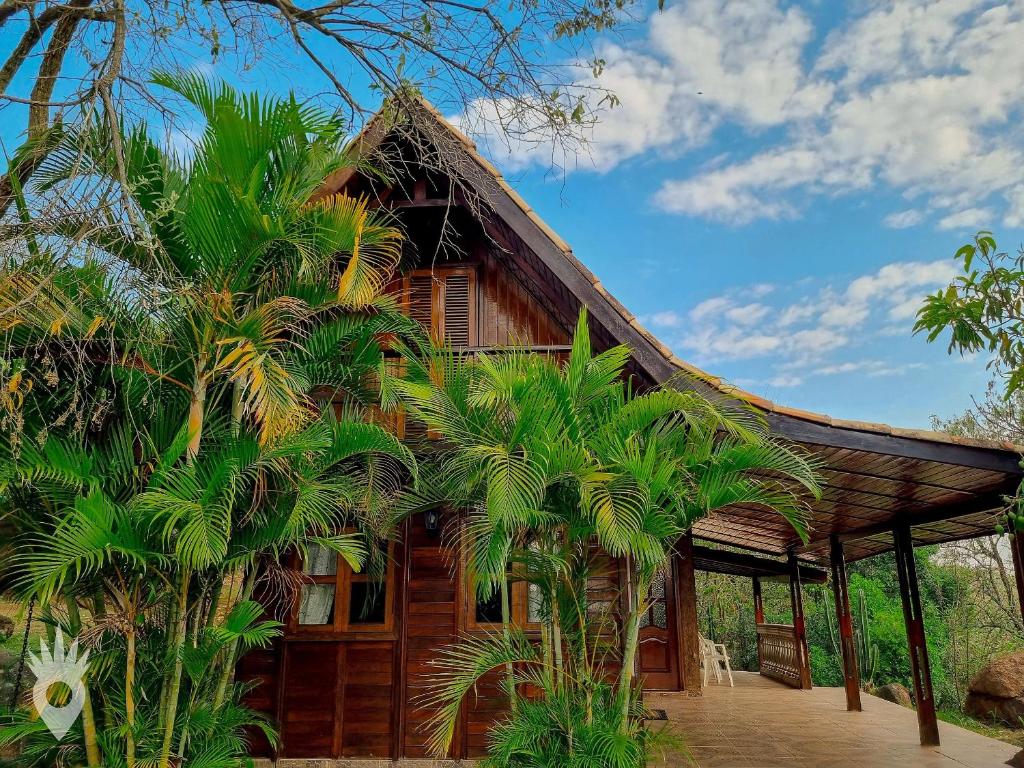 uma casa com telhado de palha e palmeiras em Chalé europeu com vista para natureza no interior em Indaiatuba