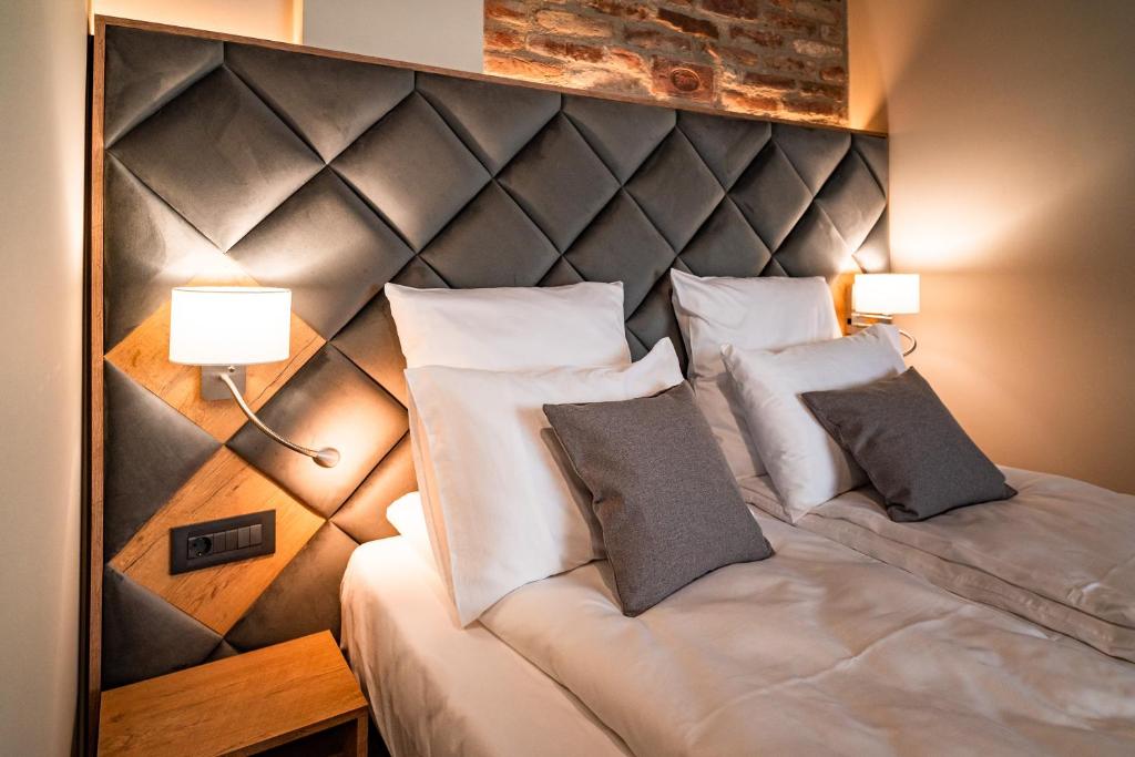 a bedroom with a large bed with two lamps at Mustang Boutique Rooms in Oradea