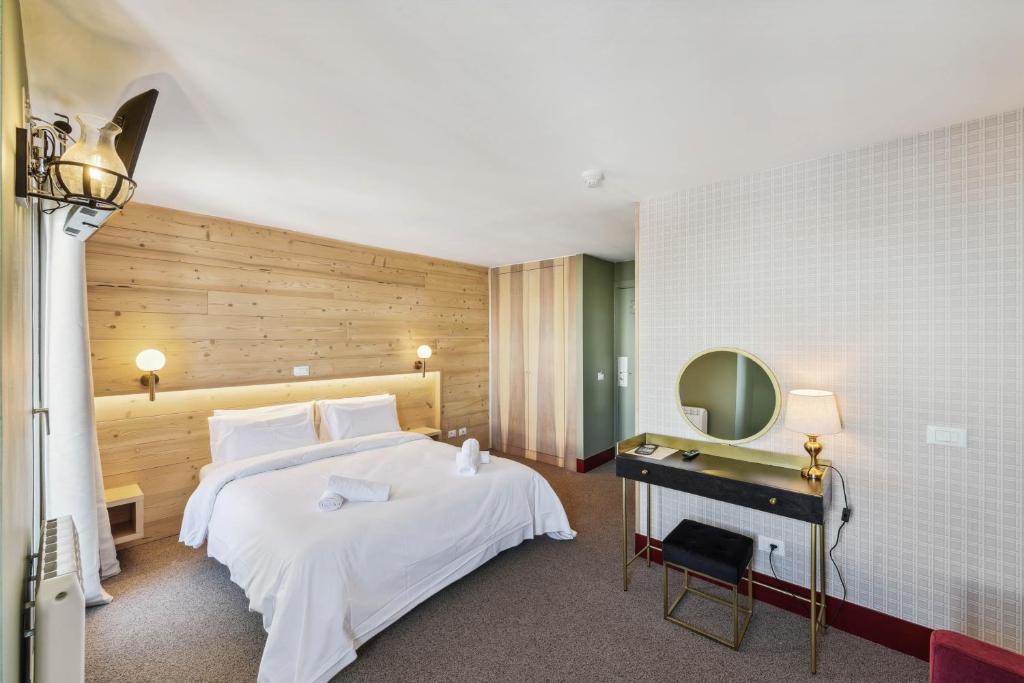 1 dormitorio con 1 cama blanca grande y espejo en HOTEL TURAN, en Les Deux Alpes