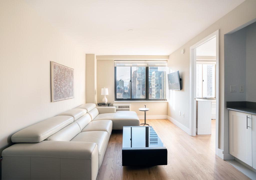 uma sala de estar branca com um sofá e uma mesa em Excellent 3 Bed 1 Bath In Mid East em Nova York