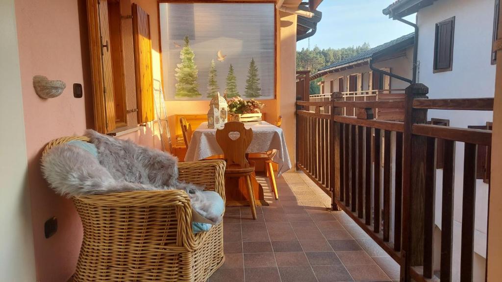 einen Balkon mit einem Tisch und Korbstühlen auf einer Veranda in der Unterkunft L'Antica Canonica di Casa Bernardi, Wi-Fi posto auto pet friendly in Trient