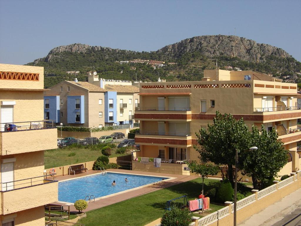 un immeuble d'appartements avec une piscine en face d'une montagne dans l'établissement Apartaments Fincasol, à L'Estartit