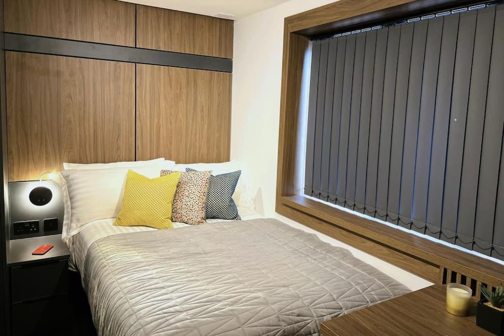una camera da letto con un letto con cuscini gialli e una finestra di Lovely 1 Bed Studio 2B near Royal Infirmary and DMU a Leicester