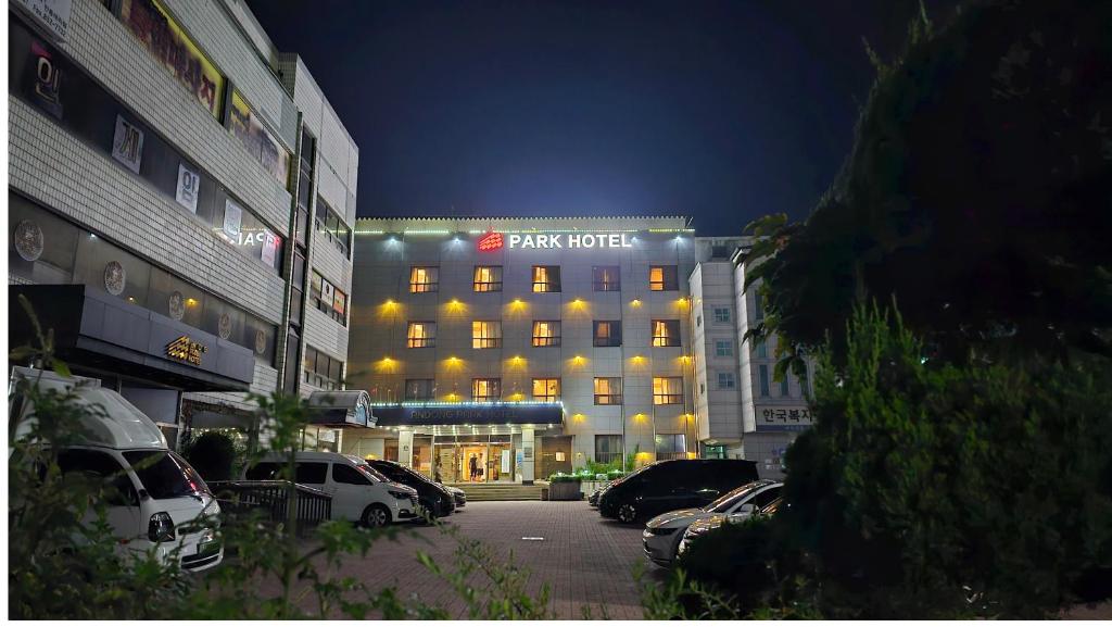 a hotel building with cars parked in a parking lot at Goodstay Andong Park Hotel in Andong