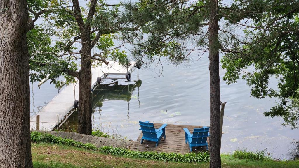 two blue chairs sitting on a dock in the water at LakePlace Bed & Breakfast 