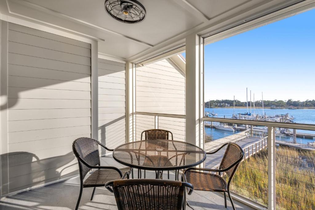 a balcony with a table and chairs and a clock at Mariners Cay 68 in Folly Beach
