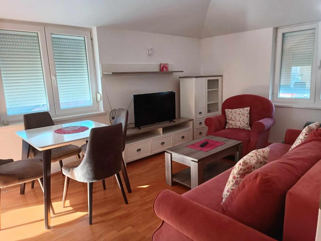 uma sala de estar com um sofá vermelho e uma televisão em Apartmani Dar Lux em Banja Koviljača