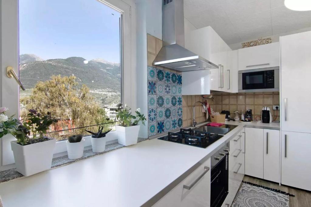 eine Küche mit weißen Schränken und einem großen Fenster in der Unterkunft MARY HOUSE @ in Sondrio