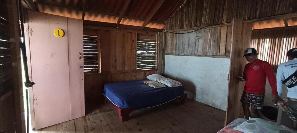um quarto com uma cama e dois homens de pé nela em Cabaña privada en las islas de Guna Yala Isla icodub em Achoertupo